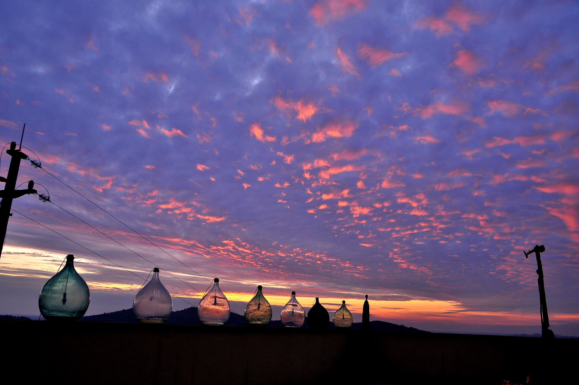 Evening sunset glow over glass demijohns on the Klinec terrace in Medana